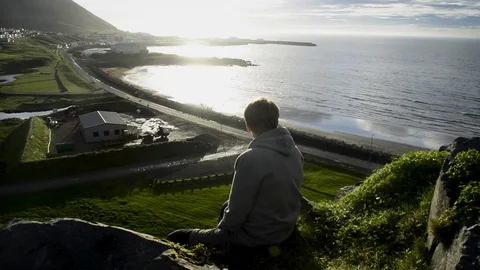 Young man sitting down and looking at Olafsvik,Silhouette Opportunity Searching1 Stock Footage 83309662