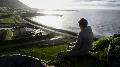 Young man sitting down and looking at Olafsvik, Silhouette Opportunity Searching Vídeo Stock 83309664