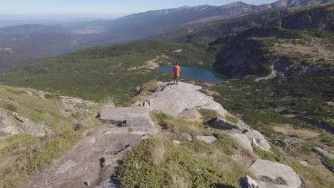 Young man sitting on edge above lake in Bulgaria Stock Footage 220499073