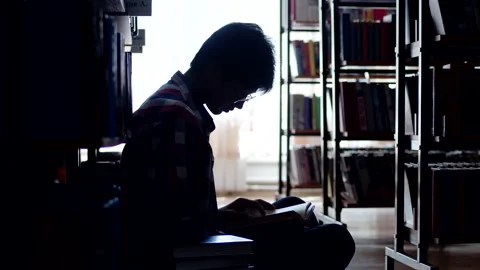 Young man is sitting on the floor in the library. silhouette of an asian man Stock Footage 194358760