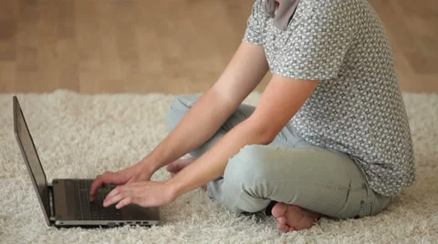 Young man sitting on floor using laptop and smiling at camera. Panning camera Stock Footage 34278392
