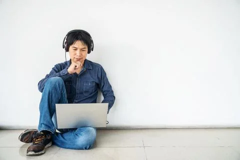 Young man sitting on the floor with using computer laptop and listening data Stock-Fotos