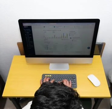 Young man sitting in front of a computer reviewing bank statistics Stock Photos