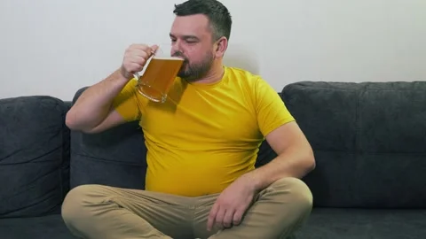 Young man is sitting on gray sofa at home in front of the TV, rejoicing and Stock Footage 166782066