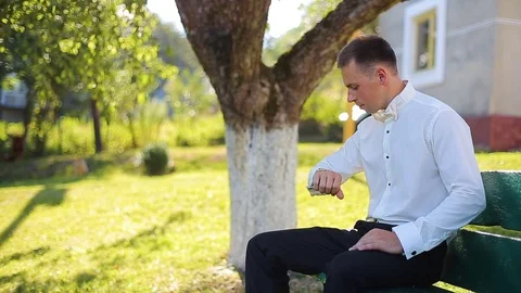 A young man sitting on a green bench in the park and waiting for a meeting Stock Footage 82807336