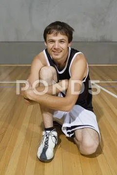 A young man sitting with his arm around one knee Stock Photos