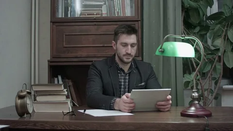 Young man sitting at his study table and having a video call via tablet 動画素材 73687400