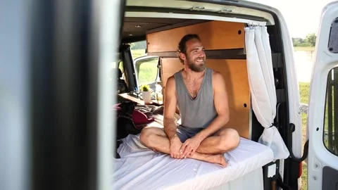 Young man sitting inside his camper van Stock Footage 135381572