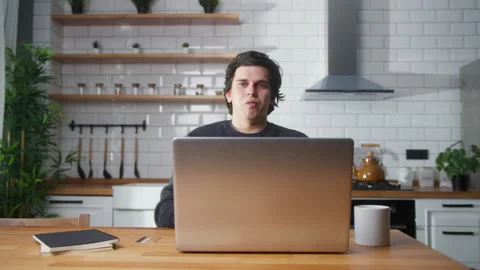 Young man sitting in kitchen at home entering credit card number on laptop .. Stock Footage 261249476