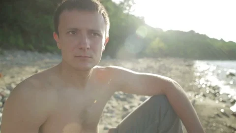 A young man is sitting on a large rock by the sea. Video stock 78712665