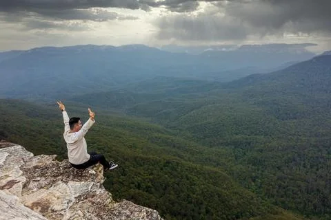 Young man sitting on the ledge of a rock outcrop Stock Photos