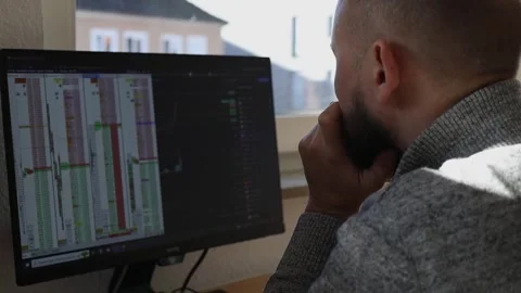 Young man sitting looking at the graph on the monitor Stock Footage 242719823
