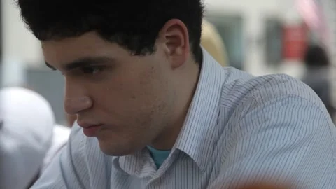 Young Man Sitting Outdoors Looking Downward in Thought Stock Footage 341323702