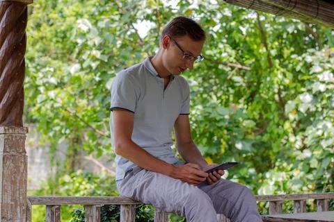 A Young Man Sitting Outside, Using a Tablet in a Peaceful and Serene Environment Stock Photos