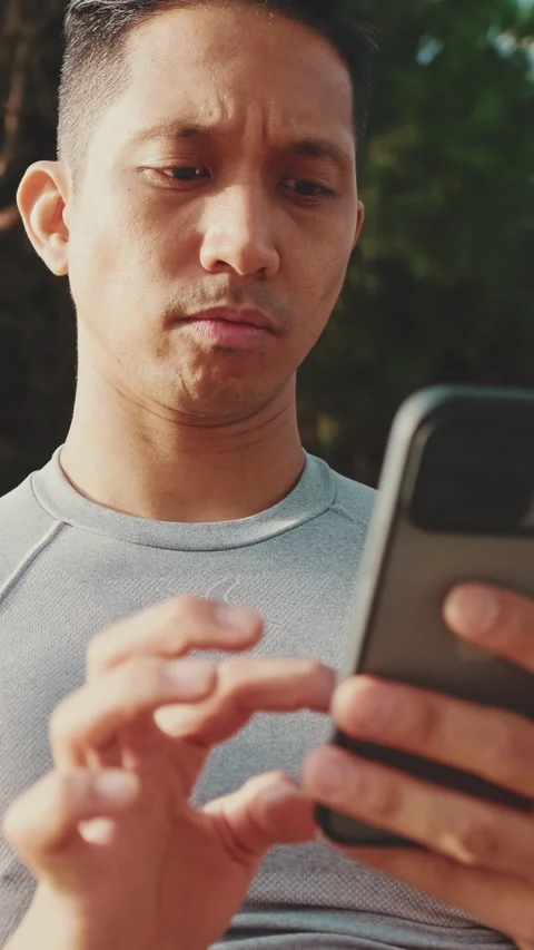 Young man sitting on a park bench uses a mobile phone Stock Footage 249732643