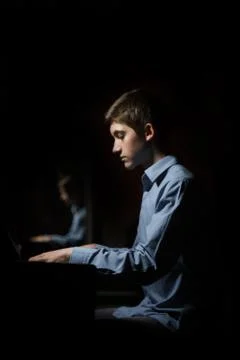 Young man sitting at the piano. boy emotionally plays the keyboard instrument Stock Photos
