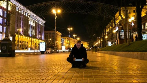 Young man sitting on the sidewalk with tablet. Smashed crowd of people. Video stock 73988497