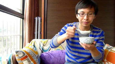 Young man sitting in the sofa and tasting self made yogurt Stock Footage 36455836