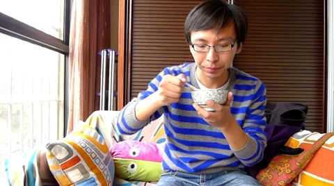 Young man sitting in the sofa and tasting self made yogurt Stock Footage 36456588