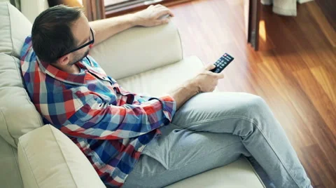 Young man sitting on sofa and watching tv HD Stock Footage 45680197
