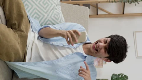 Young man sitting on sofa and punching his lap Video stock 219397388