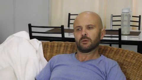 A young man sitting on the sofa with interest watching TV. Vídeo Stock 145315932