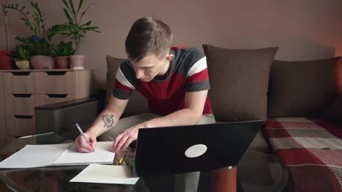 Young man sitting on sofa with laptop, working from home concept. remote work. Stock Footage 212611492