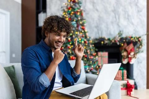 A young man sitting on sofa in the living room on a winter day for Christmas. A Stock Photos