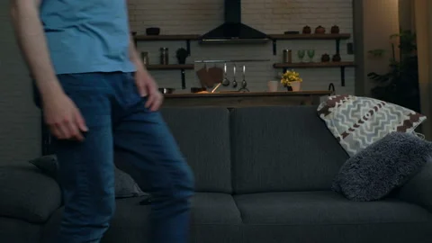 Young man sitting on the sofa, taking remote control tv and turn on TV. Stock Footage 108610964