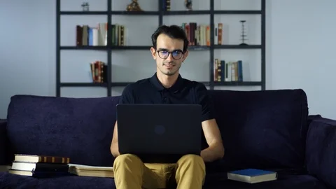 Young Man Sitting on sofa, typing on laptop, working at home, Education, New Stock Footage 93254015