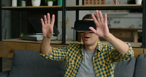 Young man is sitting on sofa in virtual reality headset Stock Footage 113622323