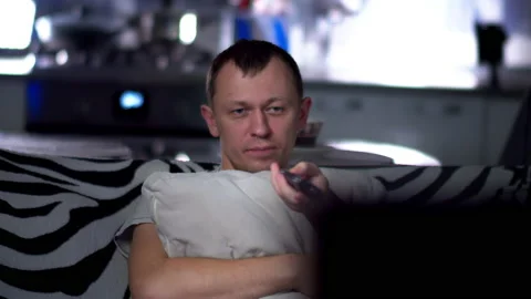 A young man is sitting on the sofa , watching TV, camera movement Stock Footage 132735513