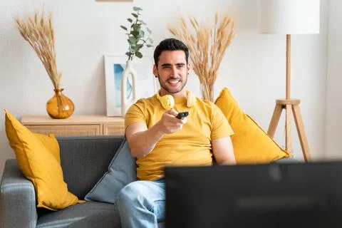 Young man sitting on sofa watching TV. Stock Photos