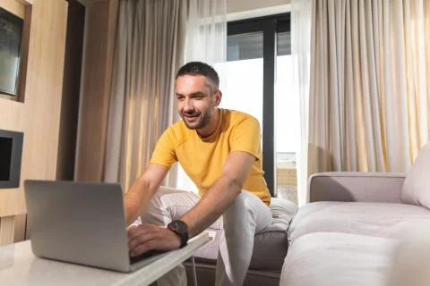 Young man is sitting on sofa while using laptop Stock Photos