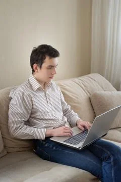 Young man sitting on sofat and using laptop at home Foto stock