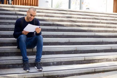 Young man sitting on steps reading a letter Stock Photos