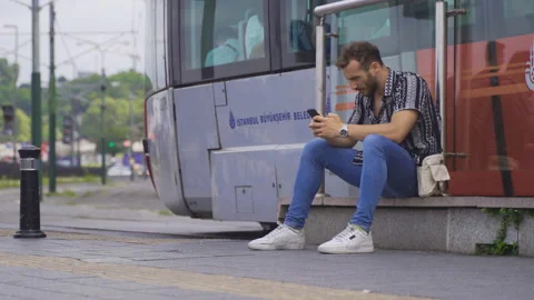 Young man sitting on the steps in the street texting on the phone. Stock-Footage 212680345