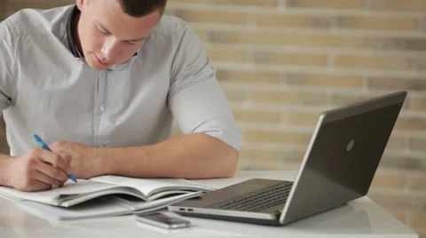 Young man sitting at table and studying with laptop Stock Footage 28390746