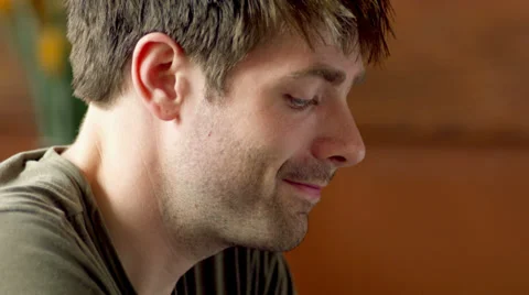 A young man sitting at a table in a cafe looks into the camera and smiles Stock Footage 33993269