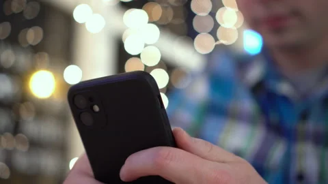 A young man is sitting at a table in a cafe in the evening and texting on the Stock Footage 166677788