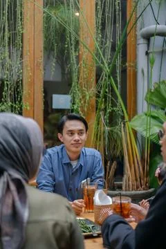 Young man sitting at a table in a cafe with friends, enjoying a conversatio.. Foto stock