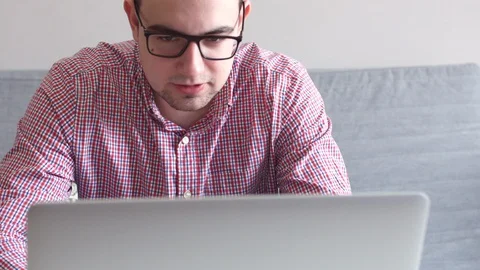 Young man sitting at table drinking coffee, talking to a friend on video call on Stock Footage 87171069