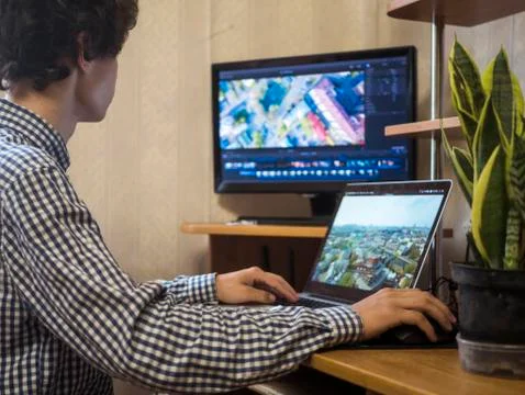 Young man sitting at the table editing video using laptop and external monito Foto stock