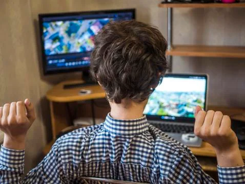 Young man sitting at the table editing video using laptop and external monito Stock Photos