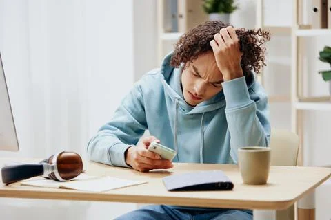 A young man sitting at a table in front of a computer freelance interior Stock Photos