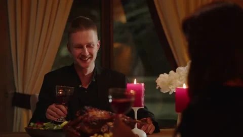 A young man sitting at a table with a glass in his hands in front of his lady Video stock 237594870