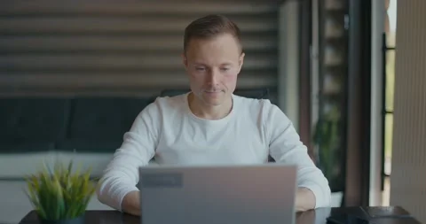 Young man sitting at table with laptop is satisfied with the work done Video stock 197817189