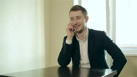 Young man is sitting at the table in the office and making telephone call. Stock Footage 62926728