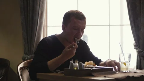 A young man sitting at a table in a restaurant eating a salad of vegetables Stock Footage 106253190
