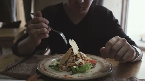 A young man sitting at a table in a restaurant eating a salad of vegetables Stock Footage 106258151